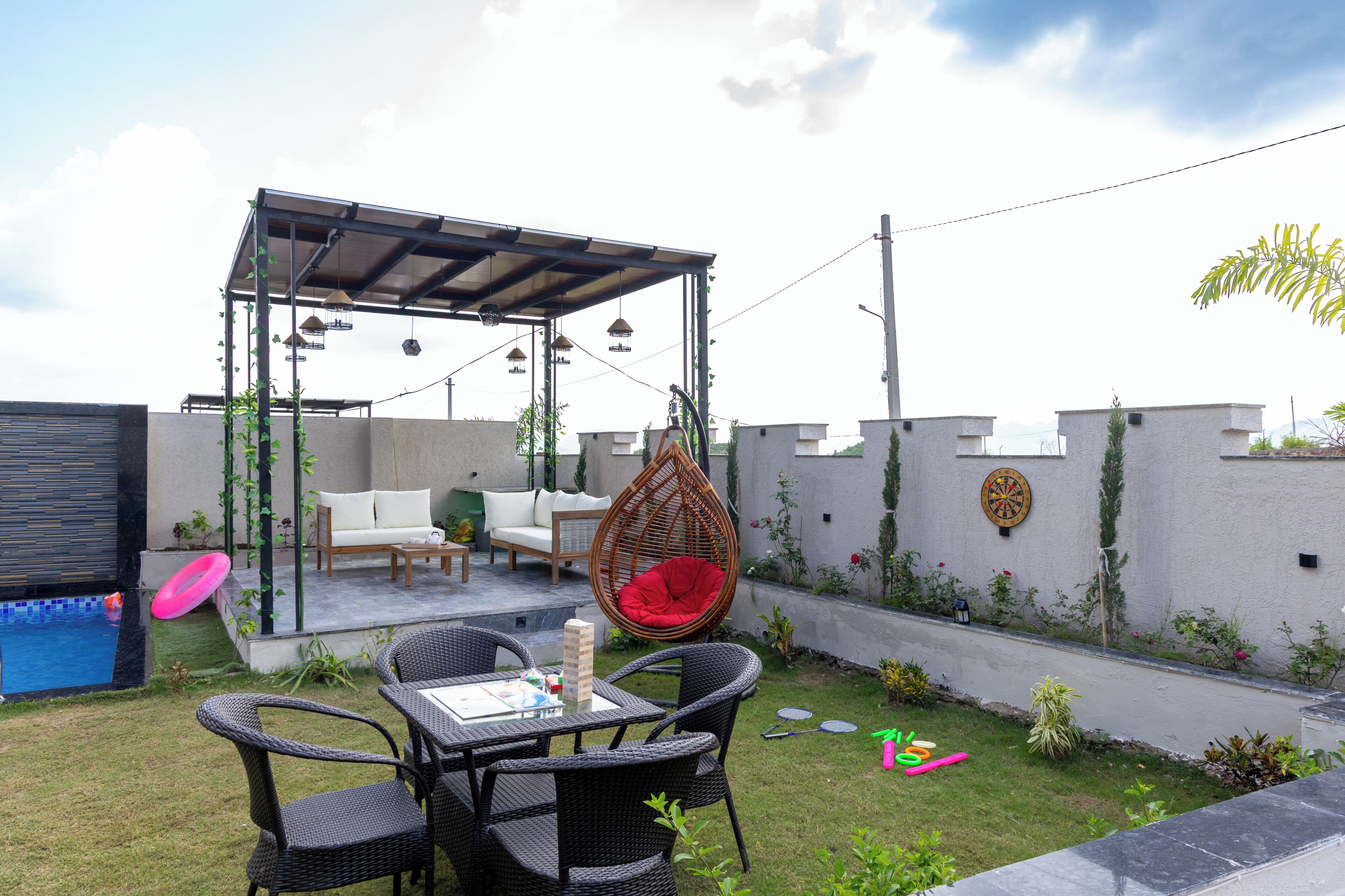 A patio area with outdoor furniture, a hanging chair, a table, and a small garden.