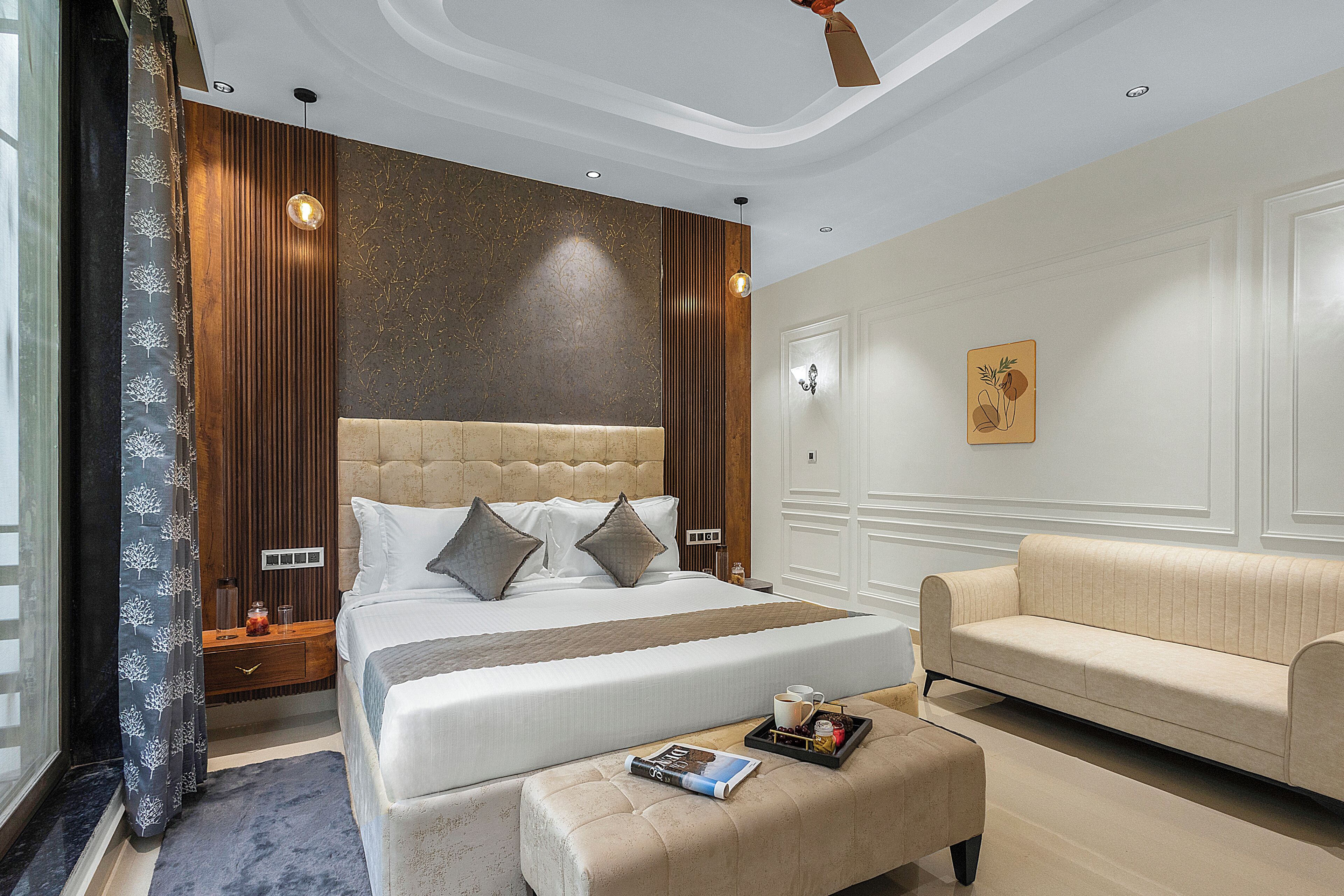 Habitación de hotel con una cama grande, un sofá, una zona de lectura y un ventilador de techo.