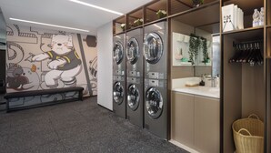 Un cuarto de lavandería con varias lavadoras, un banco, un mural en la pared, un lavabo y un espejo.
