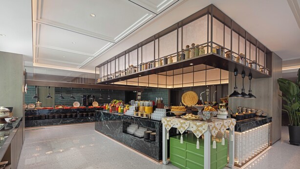 Una cocina moderna con encimera de mármol, un mueble de almacenaje verde y un entresuelo con estanterías.