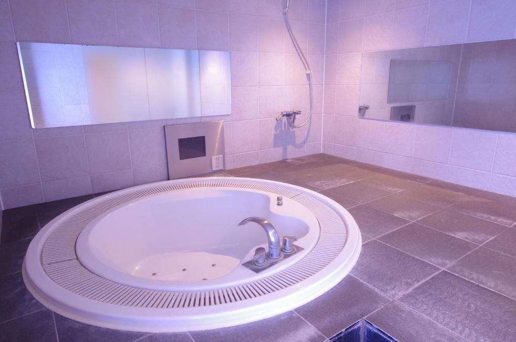 Un baño con una bañera redonda, un lavamanos, una ducha y un espejo.