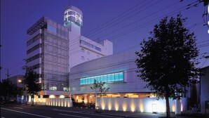 Un hotel moderno con una torre destacada, un amplio frente de vidrio y una entrada bien iluminada.