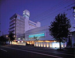 Un hôtel moderne doté d’une tour imposante, d’une grande façade en verre et d’une entrée bien éclairée.