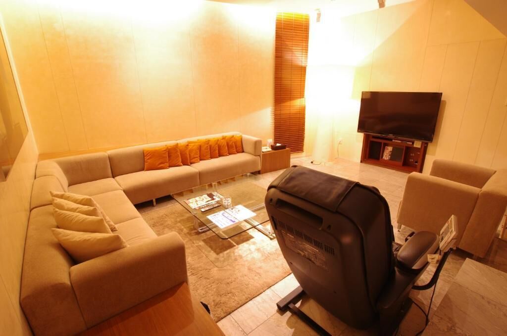 A living room with a sofa, coffee table, TV, and a black chair.