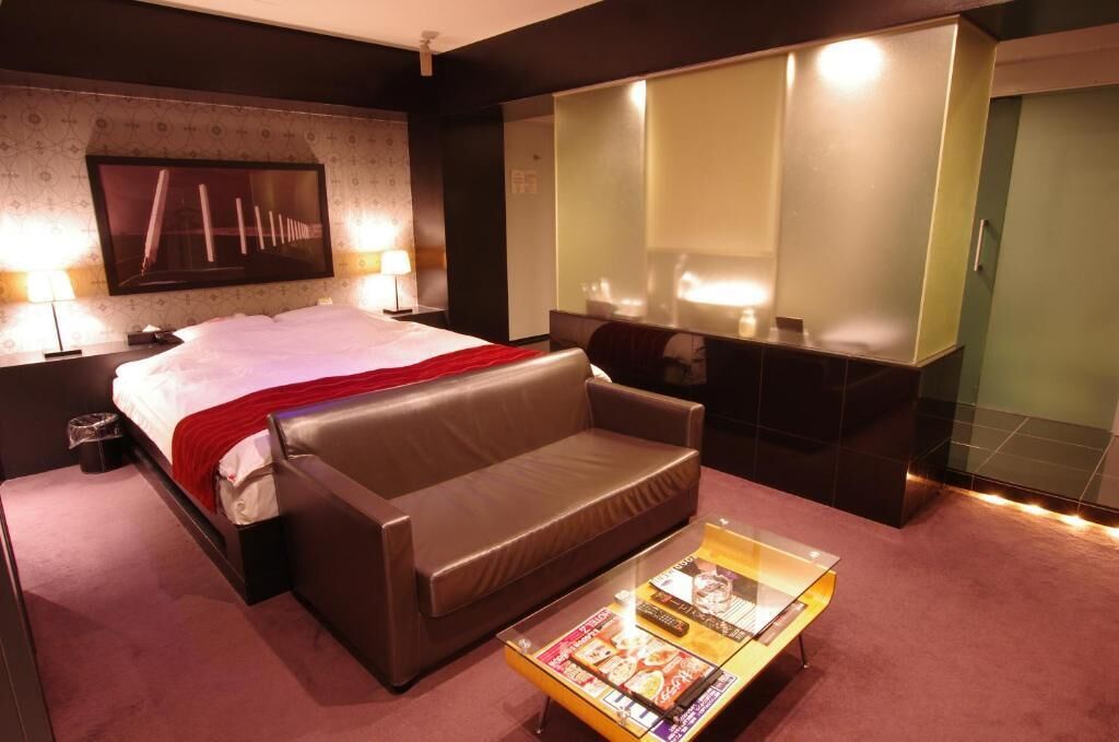 Une chambre d’hôtel comprenant un lit, un canapé, une table basse, un miroir et un téléviseur.