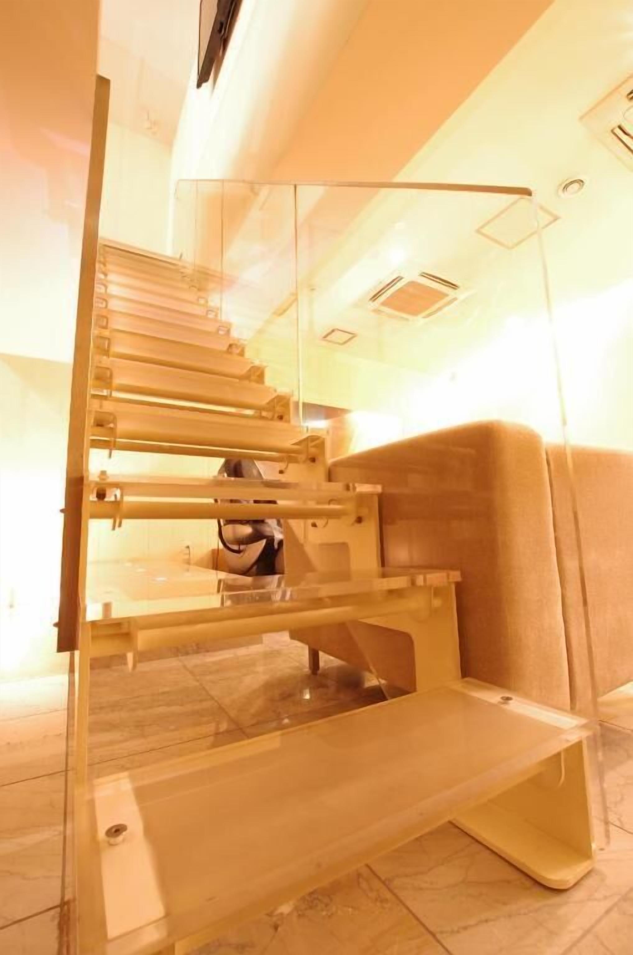A staircase with glass railings and a person descending.