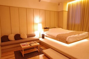 Une chambre d’hôtel avec un lit, un canapé, une petite table et une lampe.