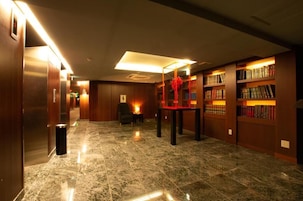 A lobby with marble flooring, wooden walls, a reception desk, and a bookshelf.