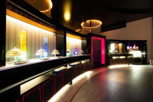 Un hall d’hôtel moderne avec un long comptoir où sont exposés divers produits alimentaires, un éclairage d’ambiance et un espace bar.