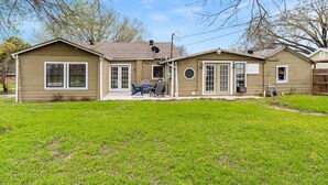 A two-story house with a front yard, satellite dish, and a small patio with outdoor furniture. - Charming Home Near Stockyards & Trinity Trails Central Fort Worth (River Oaks)