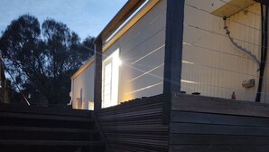 Un bâtiment moderne avec un escalier menant à une porte, le tout entouré d’arbres.