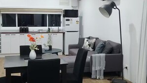 Une cuisine moderne avec un coin repas, un canapé gris et une lampe sur pied.