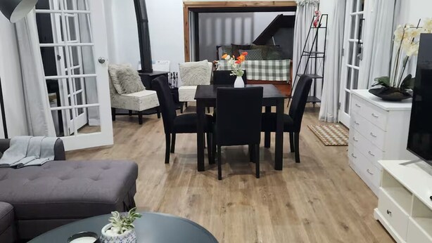 Un salon moderne comprenant un coin repas, un canapé, un téléviseur et un escalier menant à un niveau supérieur.