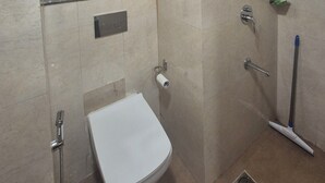 Une salle de bain équipée de toilettes, d’une douche et d’un porte-serviettes.