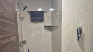 Une salle de bain avec une douche, un lavabo, une serpillière et un seau.