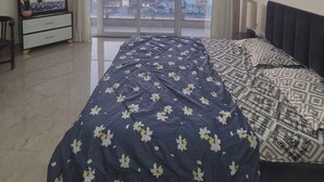 Une chambre à coucher comprenant un lit, un ventilateur de plafond, une commode, un miroir et une vue sur la ville grâce à de grandes fenêtres.