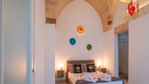 Ein Schlafzimmer mit einem Bett, zwei Nachttischen, einer Wanduhr und einem Spiegel.