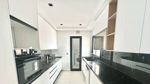 Een moderne keuken met witte kastjes, zwarte aanrechtbladen en een ingebouwde oven.