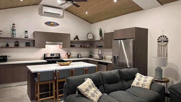 Une cuisine moderne dotée d’un îlot central, de tabourets de bar, d’un réfrigérateur et d’un ventilateur de plafond.