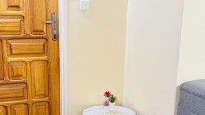 A wooden door, a small round table with a vase, and a grey sofa in a corner.