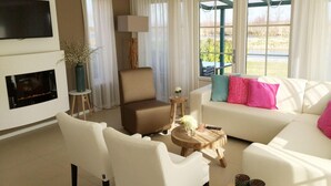 A living room with a fireplace, a sofa, a chair, a small table, and a TV mounted on the wall. - Alkmaar Cozy Dutch Villa (West-Graftdijk)