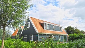 A two-story house with a sloped roof, surrounded by lush greenery. - Alkmaar Cozy Dutch Villa (West-Graftdijk)