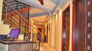 A hotel lobby with a staircase, a desk with a computer, and a ceiling fan. - Hotel Jacs Inn (Guwahati)