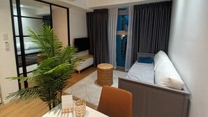 Een moderne hotelkamer met een bed, een televisie, een plant en uitzicht op de stad.