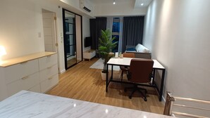 Een modern appartement met een eethoek, een kleine keuken, een woonkamer met televisie en een balkon met uitzicht.