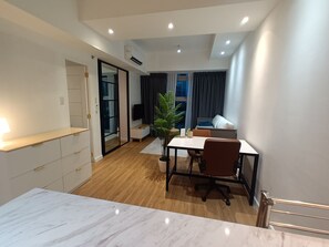 A modern apartment with a dining area, a small kitchen, a living room with a TV, and a balcony with a view. - Luxurious 1 Bedroom at AVANT in BGC (Taguig)