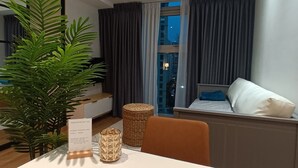 Een moderne kamer met een eettafel, een potplant, een rieten mand en een bed met een kussen.