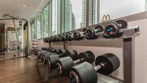 A gym with a row of dumbbells, a treadmill, and a mirror reflecting the room. - Deluxe studio at AVANT in BGC (Taguig)