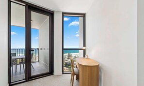 Ein Zimmer mit einer großen Schiebeglastür, die auf einen Balkon mit Meerblick führt.