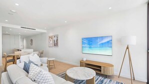 Una sala de estar moderna con una televisión de pantalla plana, una mesa de centro y un sofá.
