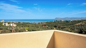 A coastal view from a balcony with a clear sky, a beach, and distant mountains. - Beautiful apartment for the whole family with view at the beach (Stalos)