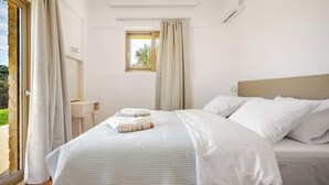 A bedroom with a bed, a window, a bedside table, and a ceiling light. - Beautiful apartment for the whole family with view at the beach (Stalos)