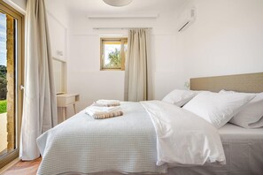 A bedroom with a bed, a window, a bedside table, and a ceiling light. - Beautiful apartment for the whole family with view at the beach (Stalos)