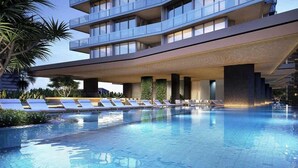 Et moderne hotel med pool, liggestole og en mangeetagers bygning.