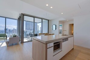 A modern kitchen with a central island, large windows, and a view of the city. - The Signature Broadbeach (Broadbeach)