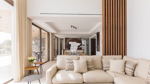 A modern living room with a beige sectional sofa, a small round table with a vase of flowers, and a large window with curtains. - CostaBlancaDreams - AIR in Calpe (Calpe)