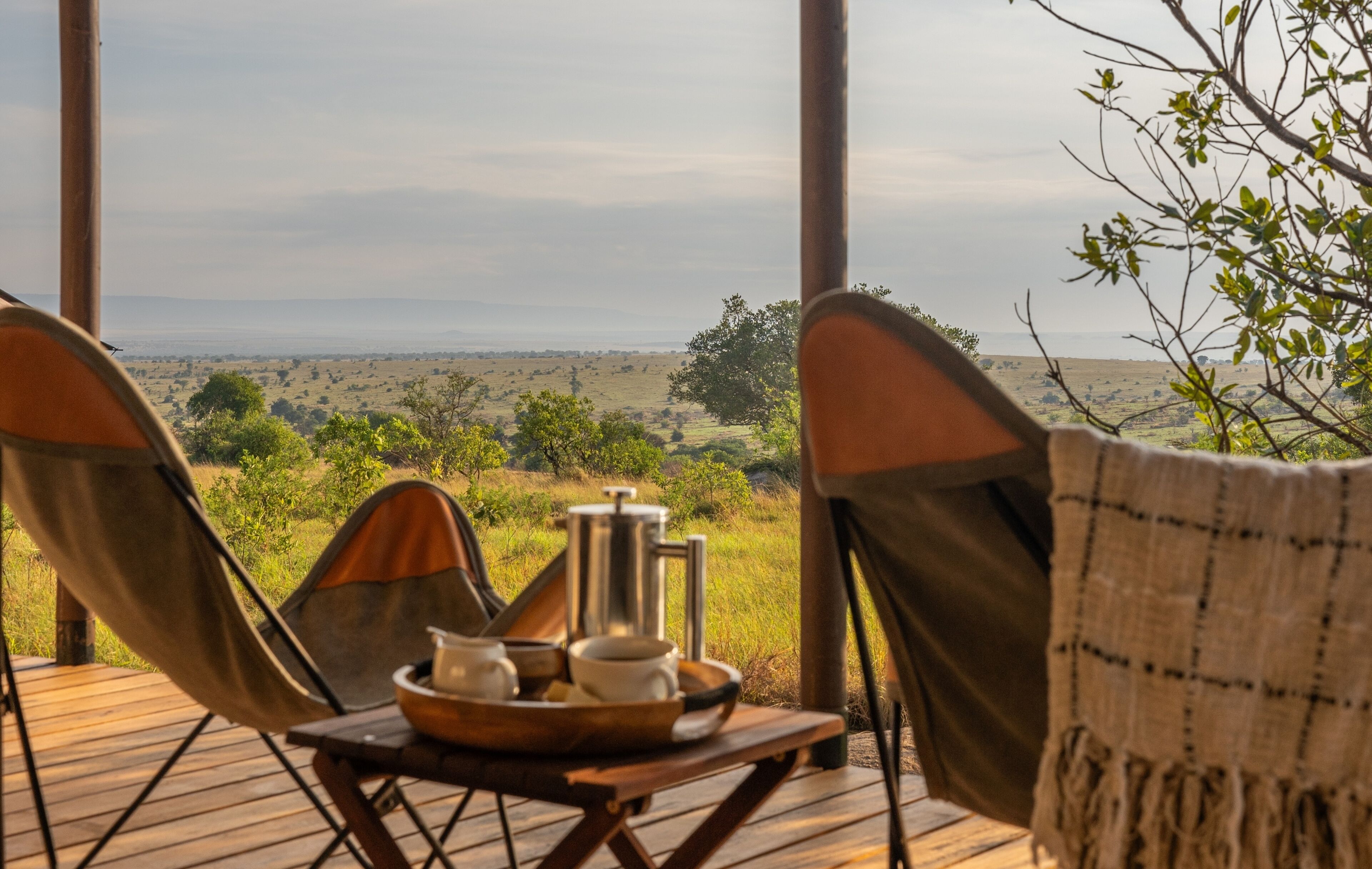 A wooden deck with two camping chairs facing a scenic view of a grassy landscape and distant horizon.
