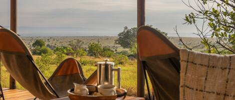 A wooden deck with two camping chairs facing a scenic view of a grassy landscape and distant horizon.