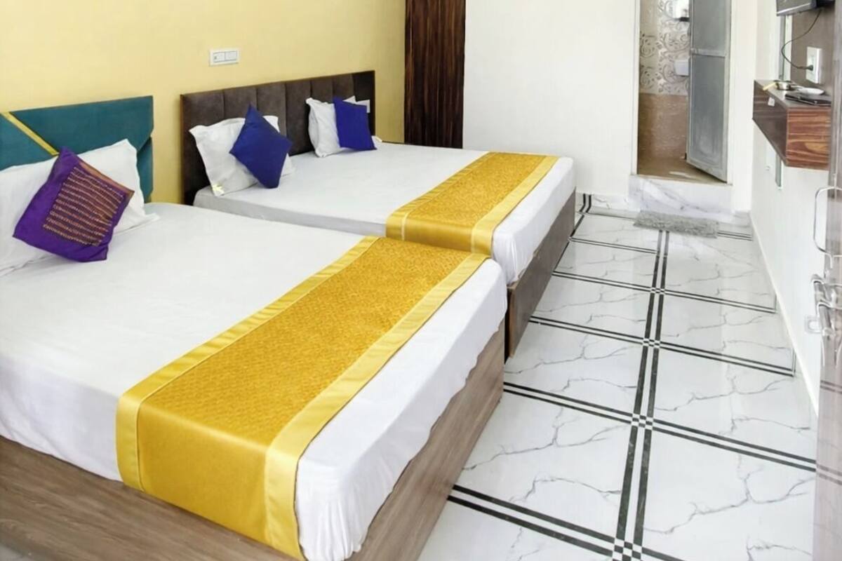 Ein Hotelzimmer mit zwei Betten, einem Fernseher, einem Badezimmer und einem Marmorboden.