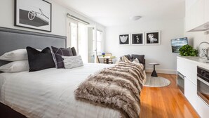 A modern bedroom with a large bed, a dining table, and a kitchen area.