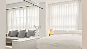 Una habitación de hotel moderna con una cama, un sofá y una mesita de noche.
