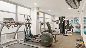 Un gimnasio con cintas de correr, elípticas, máquinas de pesas y pelotas de ejercicio.