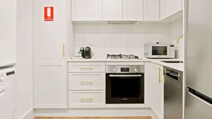 Una cocina compacta con armarios blancos, un horno Bosch, un microondas y un lavavajillas.