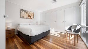 A modern bedroom with a large bed, a nightstand, a chair, and a wardrobe. - Gorgeous 2-Bed Townhouse with Patio, BBQ & Parking (Kingston)