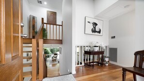 A wooden staircase leading to a second floor, a white wall with a framed picture, and a wooden bench. - Gorgeous 2-Bed Townhouse with Patio, BBQ & Parking (Kingston)
