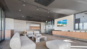 Un vestíbulo moderno con área de descanso, una recepción y un amplio ventanal con vistas.